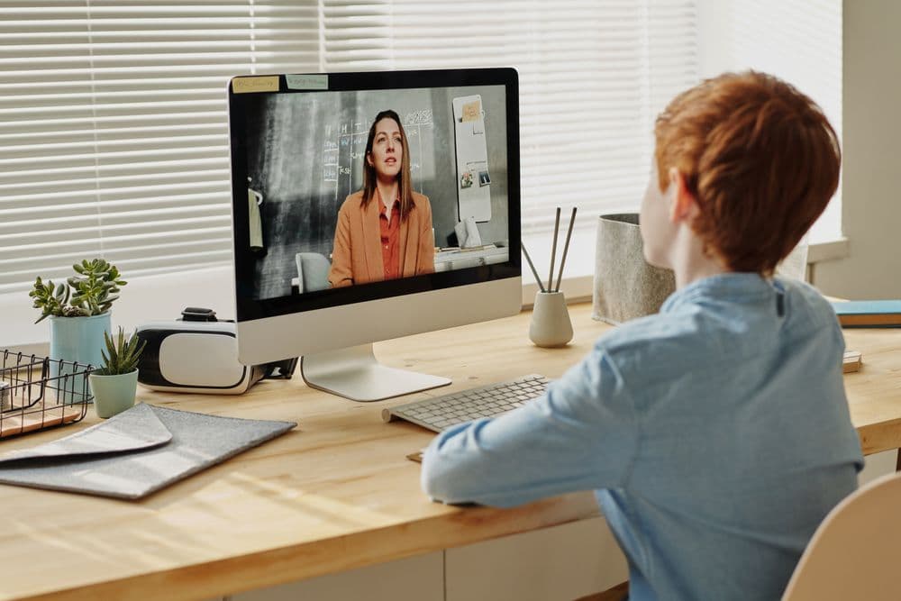 A young student learning at home with a tutor on a video call